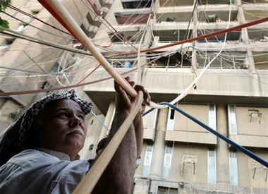 Abdul Amir Hussein connects a network of water hoses to apartments in a central Baghdad, Iraq complex Saturday, Aug. 4, 2007.