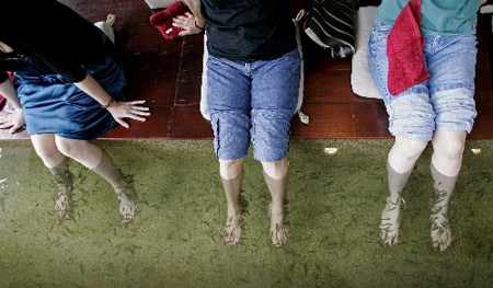 Women dip their legs into a pool of small, toothless kangal, or