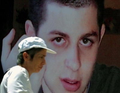 An Israeli woman walks past a poster of kidnapped Israeli soldier Gilad Shalit in Tel Aviv in this 2007 file photo. A senior Hamas official said on Sunday that if Israel rejects Hamas' demand over Gilad Shalit, the group will negotiate with Israel 'over his bones,' Israeli newspapers reported. [Agencies]