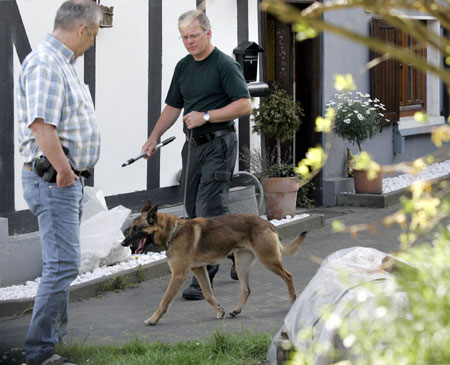 A plainclothes policeman with a dog walks outside a house where the bodies of three dead newborns were found in the town of Wenden-Moellmicke May 5, 2008. The corpses of three newborns have been found in a freezer in a private residence in western Germany and the mother of the babies taken into custody, police and local prosecutors said on Monday. In a statement, the authorities said they had launched an investigation into the deaths of the babies, which were discovered on Sunday evening after a tip from local residents in Wenden-Moellmicke, east of Cologne.