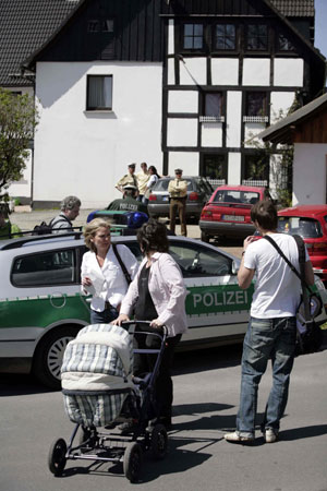 Policemen guard a house where the bodies of three dead were found in the town of Wenden-Moellmicke May 5, 2008.