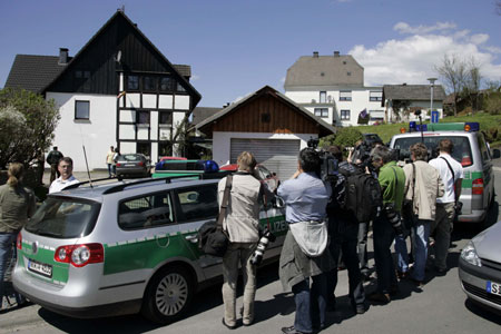 Journalists stand in front of a house where the bodies of three dead were found in the town of Wenden-Moellmicke May 5, 2008. 