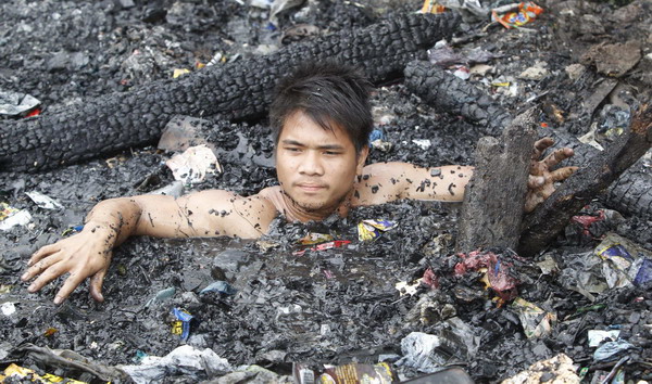 Manila slum-dwellers wade through debris after fire