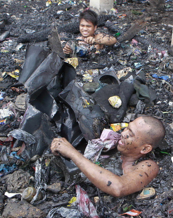 Manila slum-dwellers wade through debris after fire