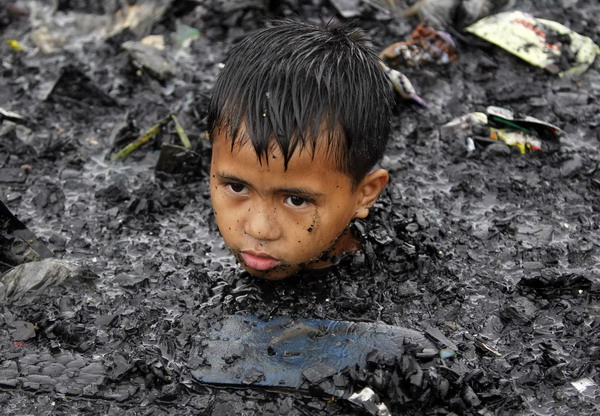 Manila slum-dwellers wade through debris after fire
