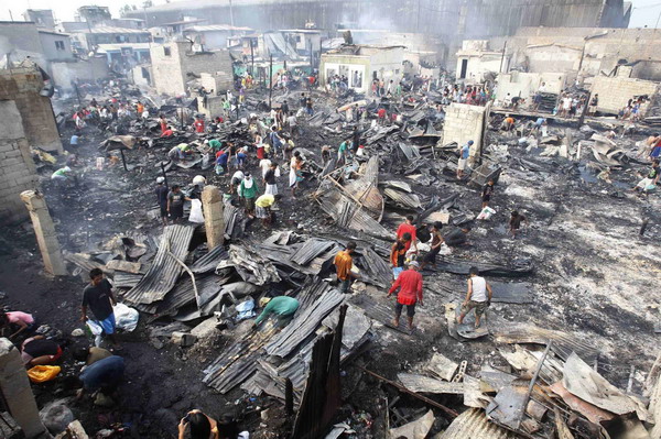 Manila slum-dwellers wade through debris after fire