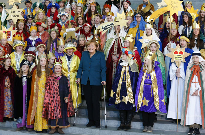 Merkel meets carols singers with crutches