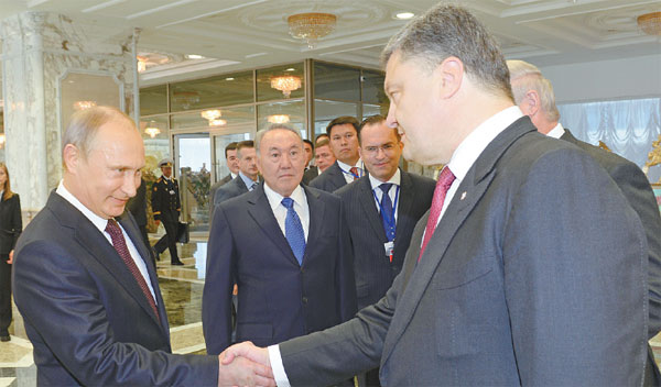 Putin shakes hands with Poroshenko