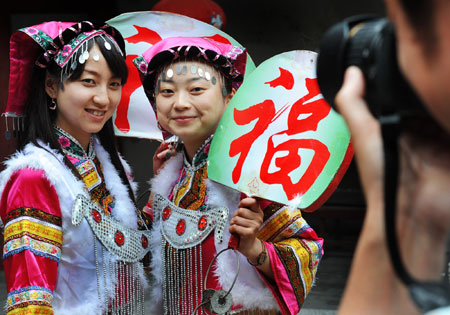 游客在为身着羌族服饰的姑娘拍照。