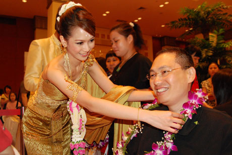 泰国小姐在现场为前来报名的市民送花环