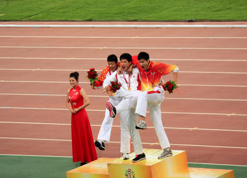 刘翔在领奖台与另外两位获奖运动员对观众做跨