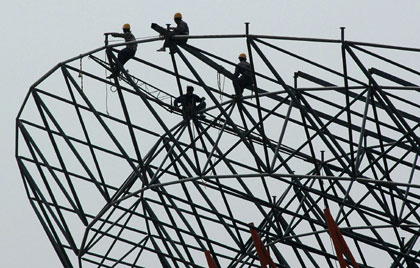 Workers perch on a steel structure at the construction site for a giant roof in Xiangfan, central China's Hubei province April 24, 2006. 