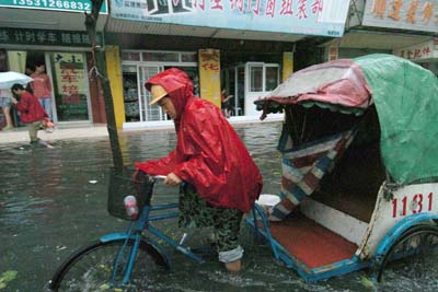 A tricycle rider wades through a flood-soaked street in Zhongshan, south China's Guangdong province May 17, 2006. Chanchu- the worst typhoon on record to enter South China Sea in May - is expected to make a landfall at Huilai and Raoping in southern Guangdong province. Almost half a million local residents have been evacuated under threat of swells, according to a Xinhua report. [Xinhua]