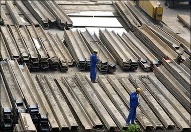 Two workers stand on tonnes of steel at a factory in Shanghai. Japan's Nippon Steel Corp. has said it is considering a possible tie-up with China's largest steelmaker Baosteel Group Corp. amid growing competition and consolidation in the industry.(AFP