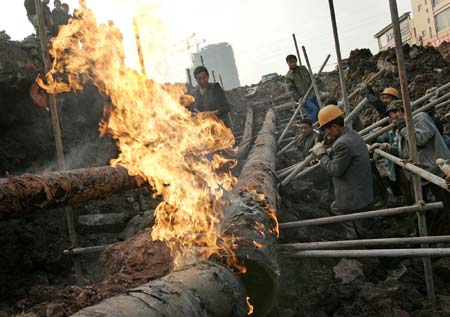 Workers repair a section of a natural gas pipeline in southwestern China's Chongqing municipality January 9, 2007. The pipeline was damaged when the road caved in, cutting off gas supply to about 300,000 people for seven hours, local media reported. Picture taken January 9, 2007. 