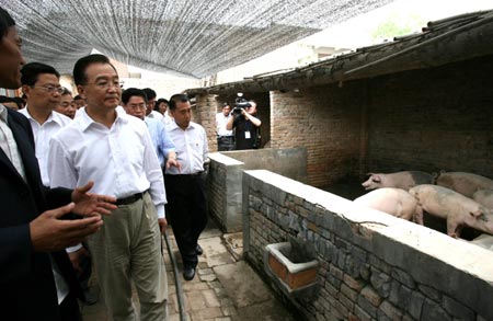 China's Premier Wen Jiabao visits a pig farm at a village in Xingping City, North China's Shaanxi Province, May 27, 2007. Wen is on an inspection tour in the province to look into the supply and demand of pork, whose prices have risen sharply in a number of cities. [Xinhua]