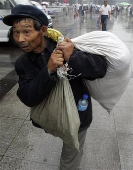 A Chinese migrant worker walks past Zhengzhou train station in Zhengzhou, central China's Henan province, Tuesday, June 19, 2007.