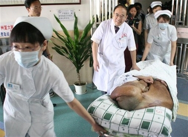 In this photo released by Fuda Cancer Hospital, Chinese man Huang Chuncai is carried on a stretcher to undergo surgery to remove a 15-kilogram tumor from his face in Guangzhou, southern China, Tuesday, July 24, 2007.