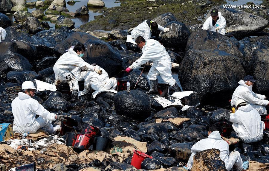 Workers clean up leaking oil on seaside of New Taipei city
