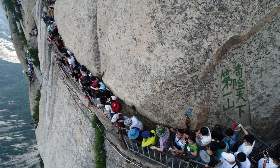 Tourists walk on plank road built on cliff at Huashan Mountain