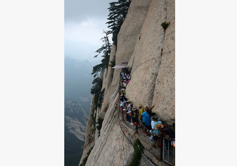 Tourists walk on plank road built on cliff at Huashan Mountain
