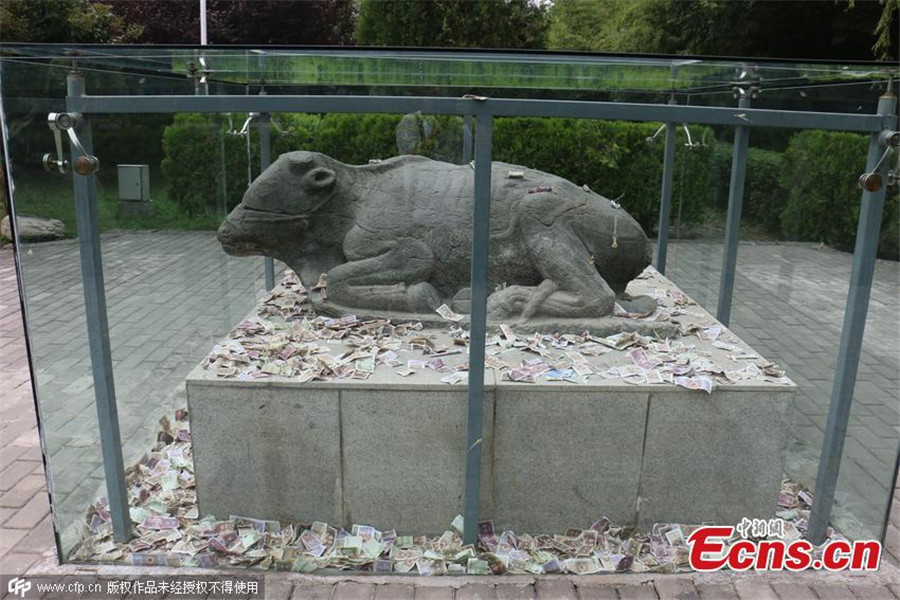 Tourists toss notes at cultural relic for luck