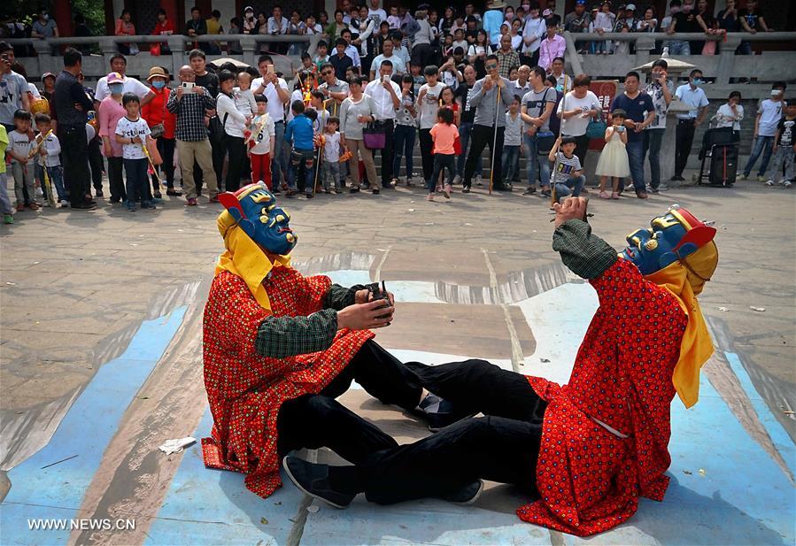 Tourists view Nuo dance at China's Yongcheng