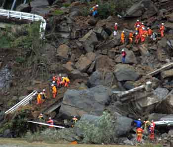 Rescue workers (bottom L) carry a survivor as other rescuers (top R) try to rescue two more survivors from a car (white colour seen amid workers) from a landslide triggered by a strong earthquake in Ojiya, northern Japan October 27, 2004. [Reuters]