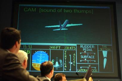 US National Transportation Safety Board members in Washington, Oct. 29, 2002, watch a computer re-creation of American Airlines Flight 587 during a meeting to discuss the New York crash. [AP/file]