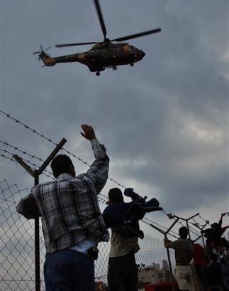 Palestinians wave at the Jordanian airforce helicopter carrying Palestinian leader Yasser Arafat as he leaves his compound in the West Bank town of Ramallah Friday Oct. 29, 2004, to seek medical treatment in Paris. [Reuters]