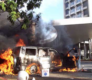 A car burns in a street in the Ivory Coast capital of Abidjan following protests, November 9, 2004. [Reuters]