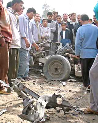 Iraqis gather around the wreckage of a car bomb after it exploded near a U.S. convoy on a highway in the northern city of Baquba, November 26, 2004. Leading Iraqi political parties, including the two main Kurdish groups closely allied to the United States, called for elections scheduled for Jan. 30 to be delayed because of Iraq's widening violence.