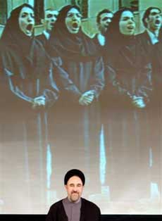 Iranian President Mohammad Khatami, listens to Iran's national anthems as he stands under a large screen television during a ceremony to mark Student Day at Tehran university in Tehran, Iran Monday, Dec. 6, 2004. In his final months in office, Iran's embattled President Mohammad Khatami admitted Monday he failed to implement his program of democratic reforms but said he refused a head-to-head collision with his hard-line opponents to save the ruling Islamic establishment. [AP]