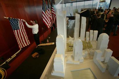 Vincent Balascio, left, removes flags from the stage after a news conference to unveil the design of a memorial for the World Trade Center victims, in New York, Thursday Dec. 16, 2004. The memorial, right, will include a forest of oak trees with a clearing for Sept. 11 gatherings and a Memorial Hall between the twin reflecting pools that will mark the footprints of the lost towers, rebuilding officials announced. [AP]