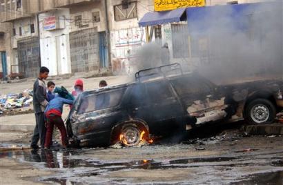 Iraqi children look at a burning car after it came under attack at Baghdad's Haifa Street Sunday Dec. 19 2004. About 30 gunmen ambushed the car Sunday in central Baghdad carrying employees of the Iraqi organization running next month's elections, killing three of the workers while two escaped unhurt, an official from the election body said. [AP]