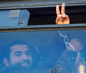 A Palestinian man flashes the victory sign out of a bus window after he was released from an Israeli jail at the Erez crossing into the Gaza Strip December 27, 2004. Israel began the release of 159 Palestinian prisoners on Monday, many of them serving the final months of their sentences, in a gesture to the new Palestinian leadership after Yasser Arafat's death. [Reuters]