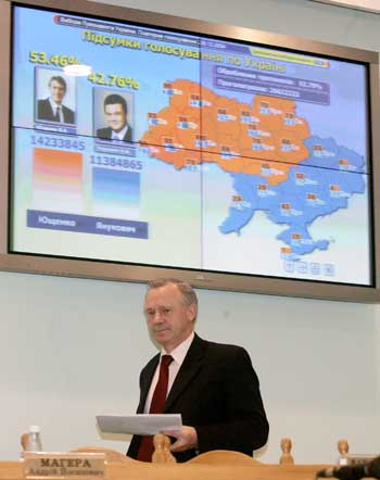 Ukraine's Central Election Commission head Yaroslav Davydovych passes by a screen showing preliminary election results as he leaves a news conference in Kiev, December 27, 2004. Western-leaning opposition leader Viktor Yushchenko took an unbeatable lead on Monday in Ukraine's re-run presidential election, claiming victory and hailing the beginning of a new era in the former Soviet republic. [Reuters]