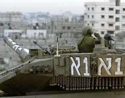 An Israeli soldier watches over the Gaza strip's Khan Younis refugee camp from atop his tank on December 30, 2004. [Reuters]