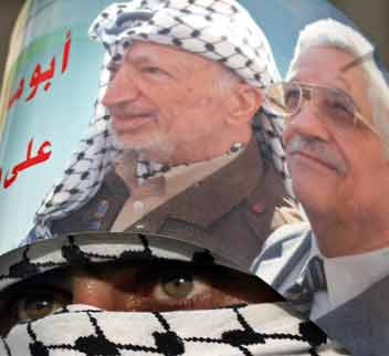 A masked Palestinian Fatah member wears an elections poster for Palestinian presidential candidate Mahmoud Abbas during during a 40th anniversary rally for the Fatah movement in the village of Yetma, near the West Bank city of Nablus January 1, 2005. Palestinians go to the polls on January 9 to choose a successor to the late Yasser Arafat. [Reuters]