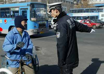 A police 
officer adnomishes 
a tricycle rider who violated traffic rules at a crossroads in Beijing. Local implementation in Beijing of the Road Traffic Safety Law went into effect this month, eight months after the enforcement of the widely debated national legislation. [newsphoto]