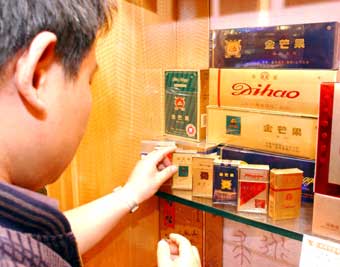 A customer chooses a pack of cigarette at a store in Zhengzhou, central China's Henan Province in this June 22, 2004 file photo. The State Tobacco Monopoly Administration said no new cigarette factories, including JV plants, will be allowed in China. [newsphoto] 