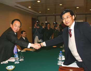 Pu Zhaozhou (R), vice chairman of the board of directors of the mainland-based Straits Aviation Exchange Commission, shakes hands with Mike Lo, chairman of Taipei Airlines Association, before their meeting with delegates from the two sides of the Taiwan Straits in Macao January 15, 2005. The two sides held talks on Saturday on landmark direct flights over the Chinese New Year holidays, a move which could ease tensions and improve the cross-Straits relations. [Reuters]