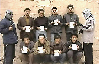 A video grab image shows eight hostages holding Chinese passports standing before a mud brick wall along with two masked gunmen. The kidnappers threathen to kill them within 48 hours unless China clarifies its stance on Iraq. [Reuters]
