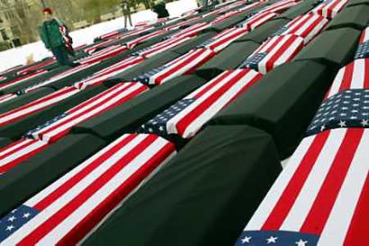 A demonstrator stands beside coffins draped with American flags as part of a protest to memorialize American soldiers who have died in the war with Iraq at Washington's Malcolm X Park, January 20, 2005. Flag-draped coffins and anti-war chants competed with pomp and circumstance on Thursday at the inauguration of President Bush along the snow-dusted, barricaded streets of central Washington. [Reuters]