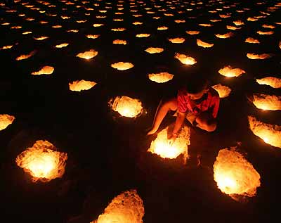 A young Thai lights candles during a vigil for tsunami victims on Patong beach in Thailand's tropical island of Phuket January 31, 2005. The Dec. 26 tsunami killed more than 5,300 people in Thailand and devastated several dozen luxury hotels at popular resorts in Phuket, Krabi and Khao Lak along its southwest coast. [Reuters]