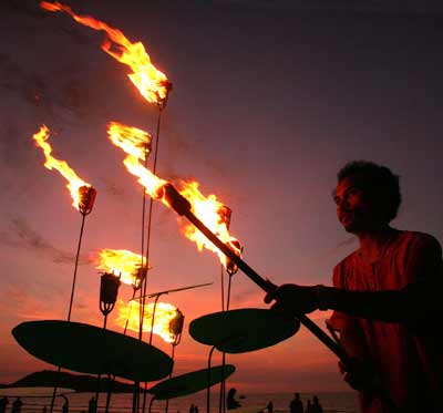 A Thai man lights torches during a vigil for tsunami victims on Patong beach, Phuket January 31, 2005.[Reuters]