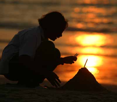 A Thai school girl places a candle in a sand before a vigil for tsunami victims on Patong beach in Thailand's tropical island of Phuket January 31, 2005. [Reuters]