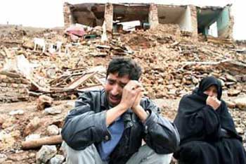 An Iranian woman and man cry after the loss of their home and family in the village of Dahouyeh near Zarand some 1000 km south east of Tehran February 22, 2005. A powerful earthquake hit mountainous region of southeast Iran, killing almost 400 people, injuring hundreds and destroying villages, officials said. [Reuters]