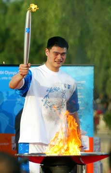 Yao Ming, a well-known Chinese basketball player and NBA Houston Rockets center, joins the 2004 Athens Olympic torch relay in Beijing's Summer Palace in this June 9, 2004 file photo. Yao is tipped by his hometown, Shanghai, as a national model worker. [newsphoto]