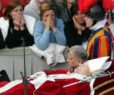 Pope John Paul II's body is carried across St. Peter's square at the Vatican, Monday, April 4, 2005 on its way for public viewing inside St. Peter's Basilica. With tens of thousands of mourners outside hoping for a glimpse of the body, 12 pallbearers flanked by Swiss Guards carried the late pontiff's body on a crimson platform from the Sala Clementina, where it had laid in state since Sunday. (AP